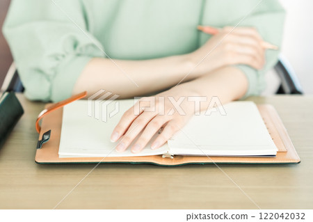 A young woman opening her notebook A young woman opening her notebook 122042032