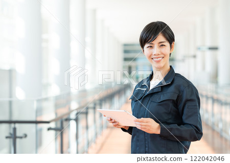 A woman in work clothes using a tablet in the office A woman in work clothes using a tablet in the office 122042046