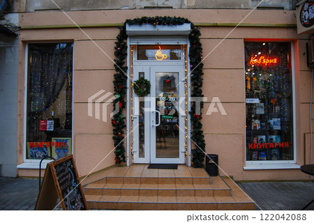 The front entrance to the coffee shop. Porch to the coffee shop with a plastic door and roller blinds. The windows are decorated with garlands. 122042088