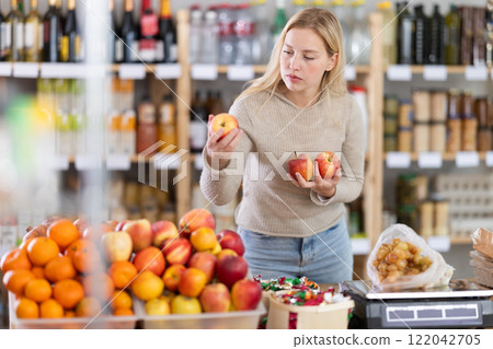 Young woman choosing apples in grocery store 122042705