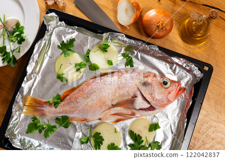 There is carcass of raw fish sea bass with spices on foil. There is carcass of raw fish sea bass with spices on foil. 122042837
