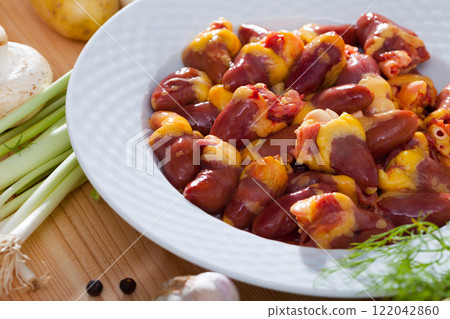 Raw chicken hearts before prepared at white plate on table 122042860