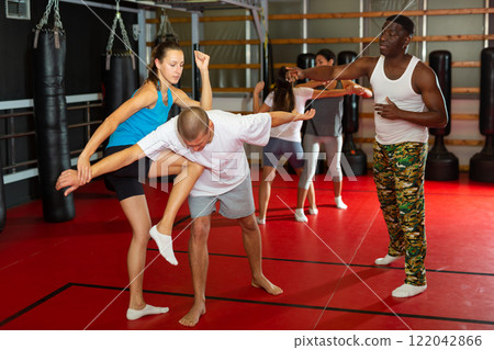 Active girl conducts painful grip on self-defense training in gym Active girl conducts painful grip on self-defense training in gym 122042866