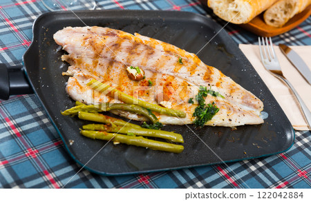 Fried bass with asparagus on the baking sheet 122042884