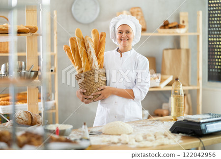Young woman baker are standing near product range in bakery kitchen. 122042956