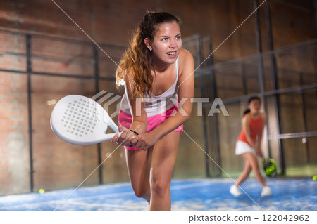 Emotional young sportswoman playing padel tennis on indoor court Emotional young sportswoman playing padel tennis on indoor court 122042962