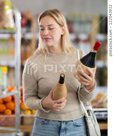 Young woman choosing wine in grocery store Young woman choosing wine in grocery store 122043012