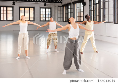 Men and women perform yoga dance in dance hall 122043015