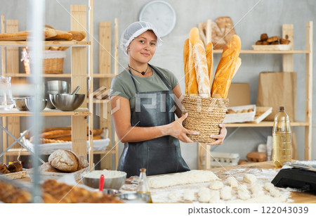 Young woman baker are standing near product range in bakery kitchen. 122043039