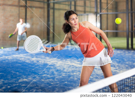 Young asian woman playing padel on a hard court Young asian woman playing padel on a hard court 122043040
