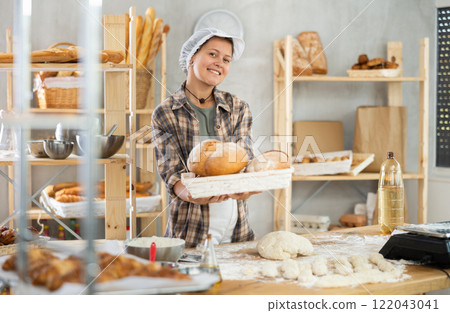 Bakery woman employee holds ready made bread of bread Bakery woman employee holds ready made bread of bread 122043041