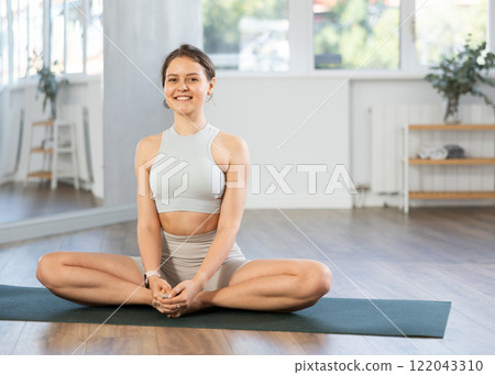 Lover of active lifestyle on yoga mat perform doing butterfly pose in gym Lover of active lifestyle on yoga mat perform doing butterfly pose in gym 122043310