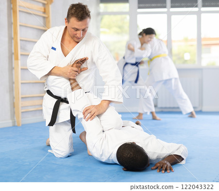 Cosmopolite sportsmen train of performing protection with wring hands during training in aikido Cosmopolite sportsmen train of performing protection with wring hands during training in aikido 122043322