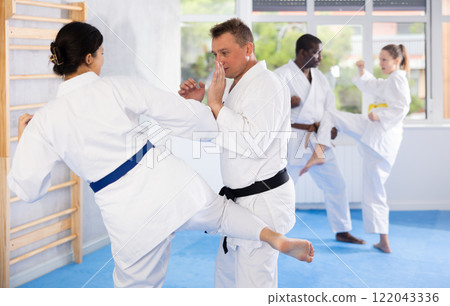 Woman and man in kimono sparring in gym during karate training 122043336