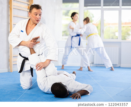 Cosmopolite sportsmen train of performing protection with wring hands during training in aikido 122043357