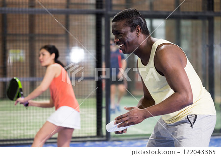 Sporty afro american man playing padel tennis indoor 122043365