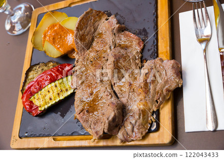 Beef steak with baked potatoes, vegetables, romesco 122043433