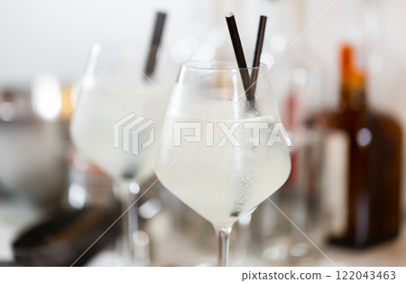 Cold cocktail with ice gin and tonic in glass goblets with straws 122043463