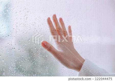 女人的手放在有水滴的窗戶上 122044475