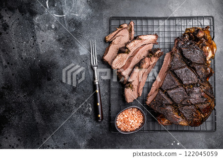 Roasted Roe Deer leg. slow cooked game meat of venison with bone. black background. top view 122045059