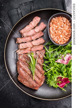 Grilled Top blade steak with salad, beef shoulder meat on a plate. black background. top view 122045068