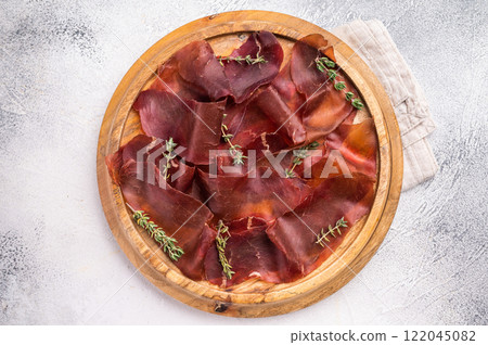 Cecina meat slices, spanish beef jamon on wooden tray white background. top view Cecina meat slices, spanish beef jamon on wooden tray white background. top view 122045082