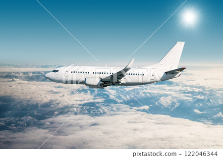 White passenger airplane flying in the air over snow covered mountains 122046344