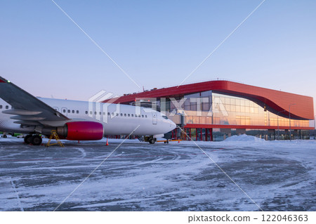 Passenger airplane parked at the terminal on the winter airport apron 122046363