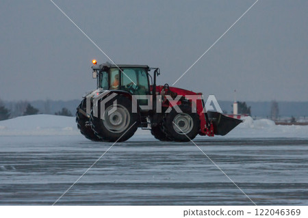 Wheel tractor rides on a winter road 122046369
