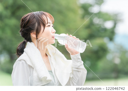 Side profile of Asian woman drinking plastic bottle water during exercise/walking break 122046742