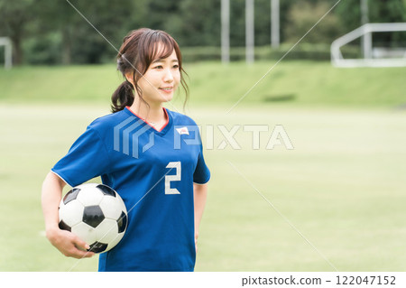 作為球迷支持者的日本女子拿著足球微笑踢球 122047152
