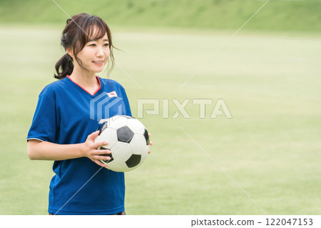 A Japanese woman who is a fan supporter playing soccer with a smile while holding a soccer ball A Japanese woman who is a fan supporter playing soccer with a smile while holding a soccer ball 122047153
