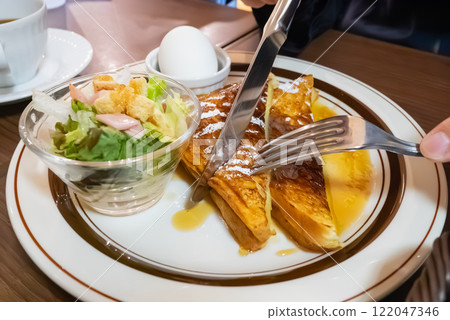 在咖啡館吃早餐。一個人正在吃塗著甜糖漿的法式吐司。 122047346