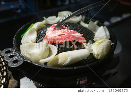 Genghis Khan is a barbecue dish made with lamb. The lamb and vegetables are grilled in an iron pot. 122049273