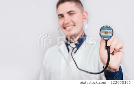 Smiling doctor showing stethoscope with Argentina flag. Argentina National Healthcare concept Smiling doctor showing stethoscope with Argentina flag. Argentina National Healthcare concept 122050395
