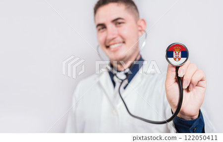 Happy doctor showing stethoscope with Serbia flag. Serbia National Healthcare concept 122050411