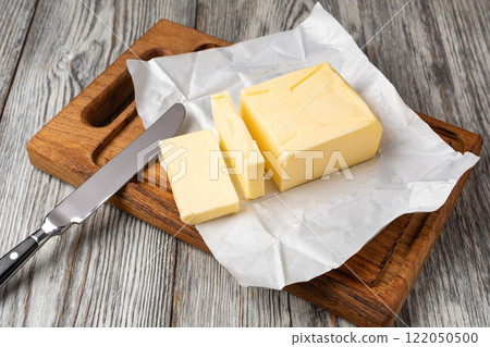 Butter slices with butter knife on wooden cutting board 122050500