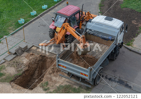 Smolensk, Russia - 08/15/2018: a tractor with a backhoe digs a pit and loads of sand a dump body Smolensk, Russia - 08/15/2018: a tractor with a backhoe digs a pit and loads of sand a dump body 122052121