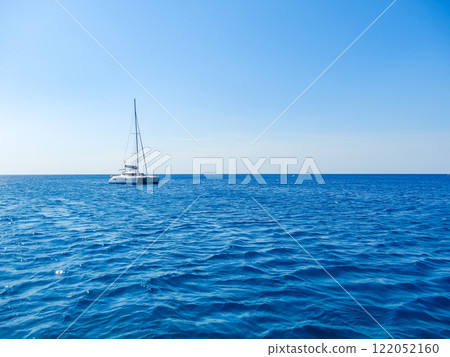 Sailboat drifting on calm blue ocean under clear sky, peaceful and serene scene. High quality photo Sailboat drifting on calm blue ocean under clear sky, peaceful and serene scene. High quality photo 122052160