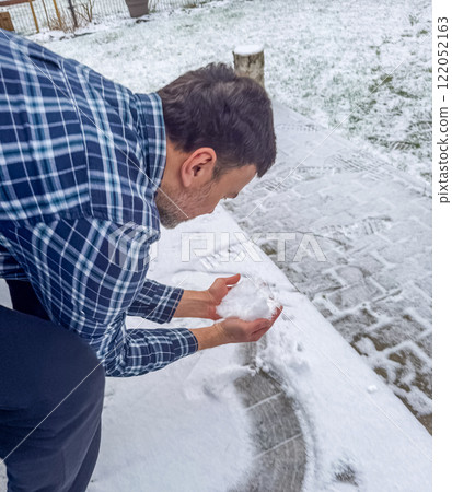 Man rubbing his face with snow in a wintery setting surrounded by trees. High quality photo 122052163