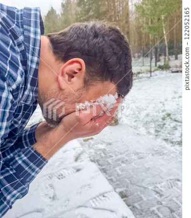Man rubbing his face with snow in a wintery setting surrounded by trees. High quality photo Man rubbing his face with snow in a wintery setting surrounded by trees. High quality photo 122052165