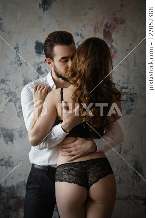 Intimate moment between a couple, a guy in office clothes hugs a girl in black underwear 122052388