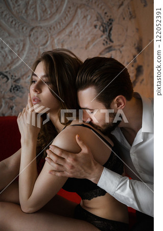 The two sit on a cozy sofa in a dimly lit room, showing a picture of desire intertwined with indifference. The two sit on a cozy sofa in a dimly lit room, showing a picture of desire intertwined with indifference. 122052391