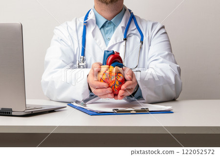 Doctor with anatomical model of human heart Cardiologist supports the heart. heart diagnose medical checkup cardiologist in examination room. Doctor with anatomical model of human heart Cardiologist supports the heart. heart diagnose medical checkup cardiologist in examination room. 122052572