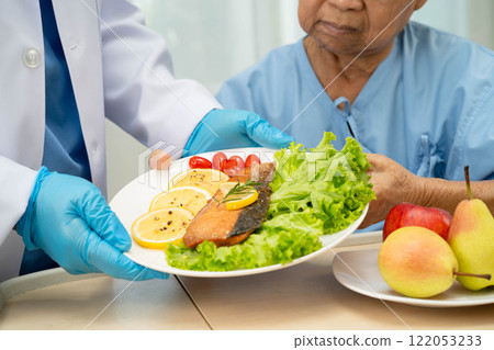 Asian elderly woman patient eating salmon stake and vegetable salad for healthy food in hospital. Asian elderly woman patient eating salmon stake and vegetable salad for healthy food in hospital. 122053233