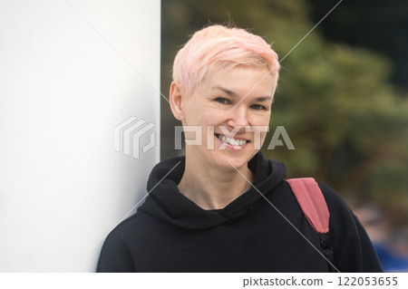 Cheerful middle-aged woman with short hair and a black jacket outdoors Cheerful middle-aged woman with short hair and a black jacket outdoors 122053655