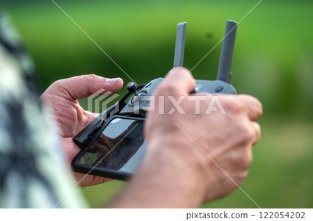 A man holding a remote control of a drone in his hand, close-up 122054202