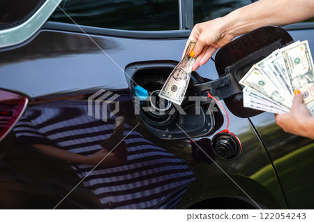 hand of woman that puts money into the tank of car, closeup, concept of expensive fuel, fuel crisis 122054243