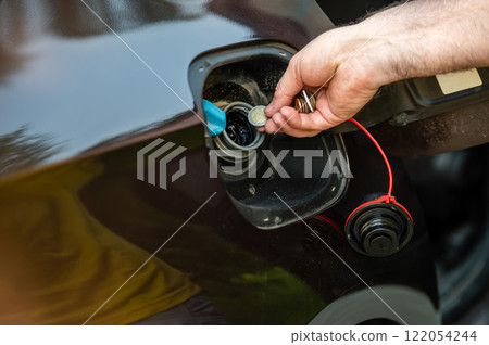 hand of man putting coins in car tank, closeup, expensive fuel concept, fuel crisis 122054244