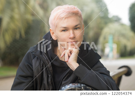 Portrait of mid adult woman in city park. Mature model traveler with elegant short haircut 122054374